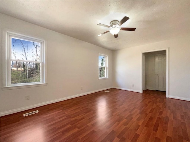 unfurnished room with ceiling fan, dark hardwood / wood-style flooring, and a textured ceiling