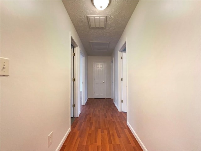 corridor with dark hardwood / wood-style floors and a textured ceiling