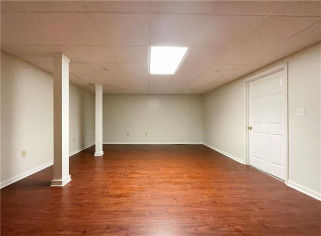 basement featuring dark wood-type flooring and a paneled ceiling