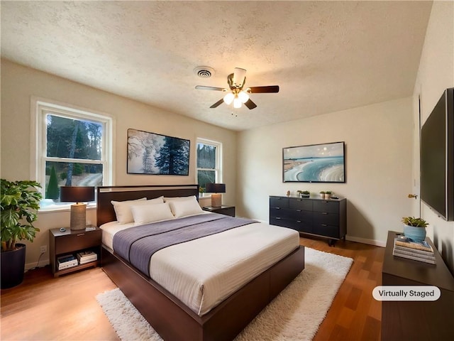 bedroom with ceiling fan, a textured ceiling, and light wood-type flooring