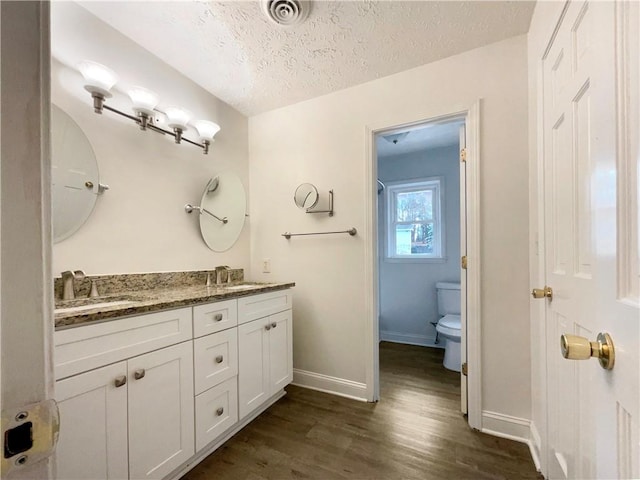 bathroom with vanity, hardwood / wood-style floors, toilet, and a textured ceiling