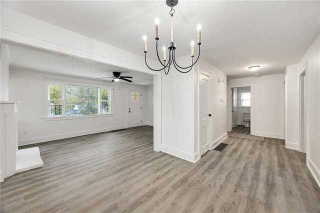 unfurnished dining area featuring ceiling fan with notable chandelier, light hardwood / wood-style floors, and a healthy amount of sunlight