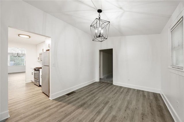 unfurnished room featuring hardwood / wood-style floors and a chandelier