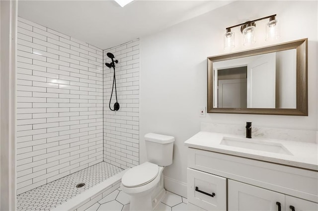 bathroom with tiled shower, tile patterned floors, vanity, and toilet