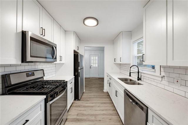 kitchen featuring stainless steel appliances, white cabinetry, and sink