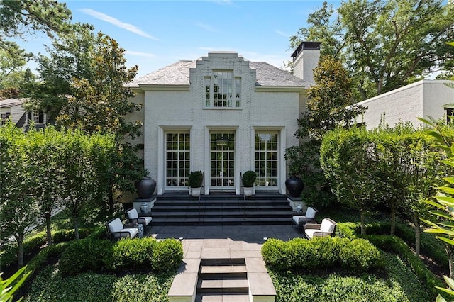 back of property featuring entry steps, brick siding, and a chimney