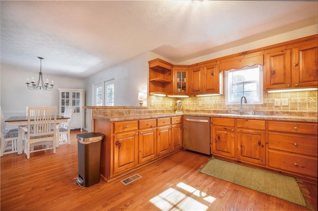 kitchen with light wood-style flooring, a sink, visible vents, dishwasher, and brown cabinetry