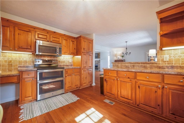 kitchen featuring visible vents, brown cabinetry, dark wood-style floors, stainless steel appliances, and open shelves