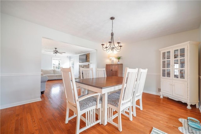 dining room with light wood finished floors, baseboards, and ceiling fan with notable chandelier