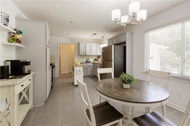 340 Monivea Ln, Roswell, GA 30075 - dining space featuring light tile patterned floors, a chandelier, a textured ceiling, and baseboards