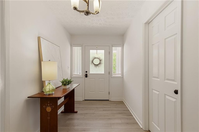 340 Monivea Ln, Roswell, GA 30075 - foyer entrance with light wood-style flooring, a chandelier, a textured ceiling, and baseboards