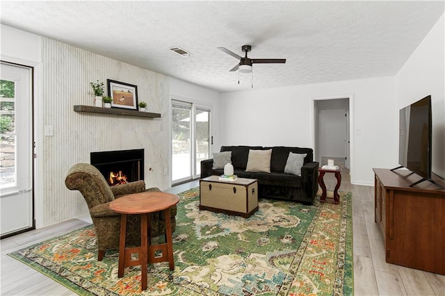 340 Monivea Ln, Roswell, GA 30075 - living area with a textured ceiling, a ceiling fan, a premium fireplace, and light wood-style floors