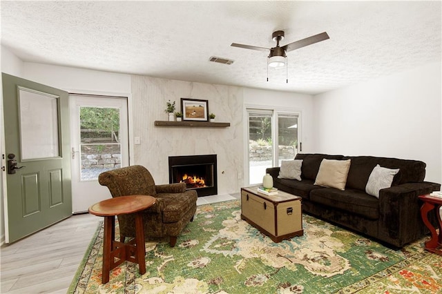 340 Monivea Ln, Roswell, GA 30075 - living area featuring a textured ceiling, light wood-style floors, a high end fireplace, and ceiling fan