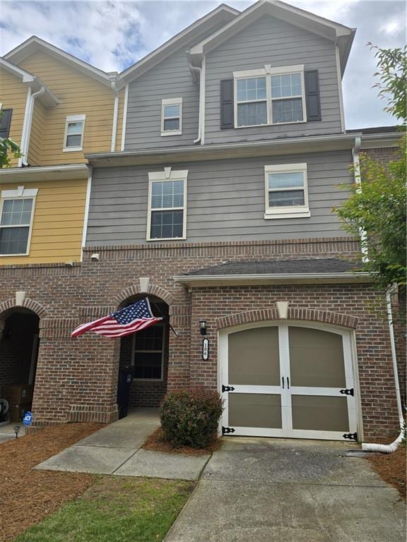multi unit property with an attached garage, brick siding, and driveway