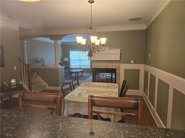 106 Trailside Way, Hiram, GA 30141 - dining space with decorative columns, a chandelier, a tile fireplace, ornamental molding, and wood finished floors