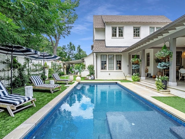 back of house with a shingled roof, brick siding, an outdoor pool, and a patio