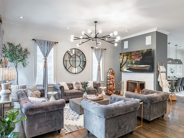 living room featuring dark wood-style flooring, a notable chandelier, recessed lighting, ornamental molding, and a lit fireplace