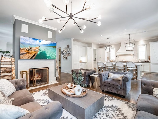 living area featuring a notable chandelier, dark wood finished floors, crown molding, and a fireplace with flush hearth