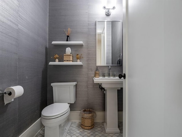 bathroom with tile patterned flooring, baseboards, a sink, and toilet