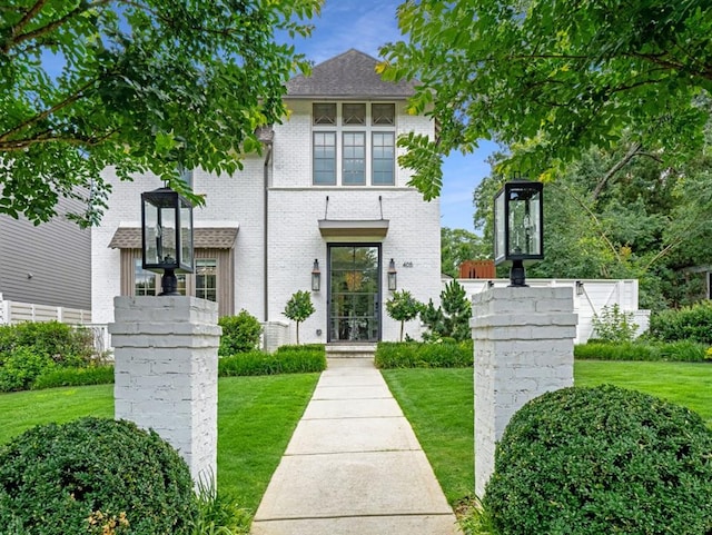 view of front facade with brick siding and a front lawn