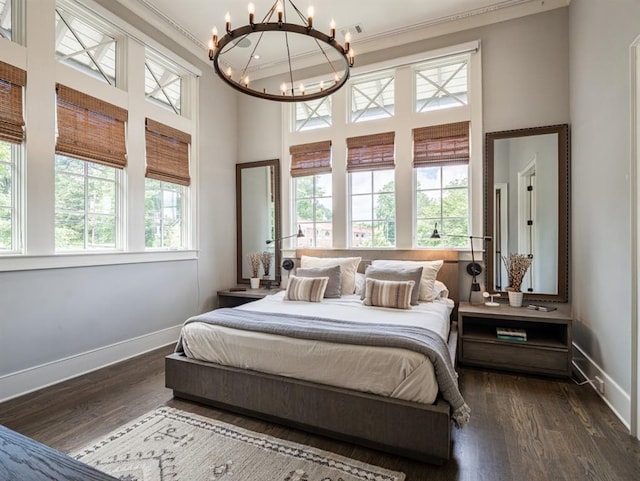 bedroom with a notable chandelier, multiple windows, and dark wood-style flooring