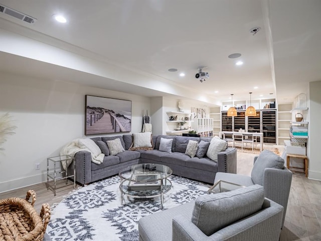 living area with light wood-style floors, recessed lighting, visible vents, and baseboards