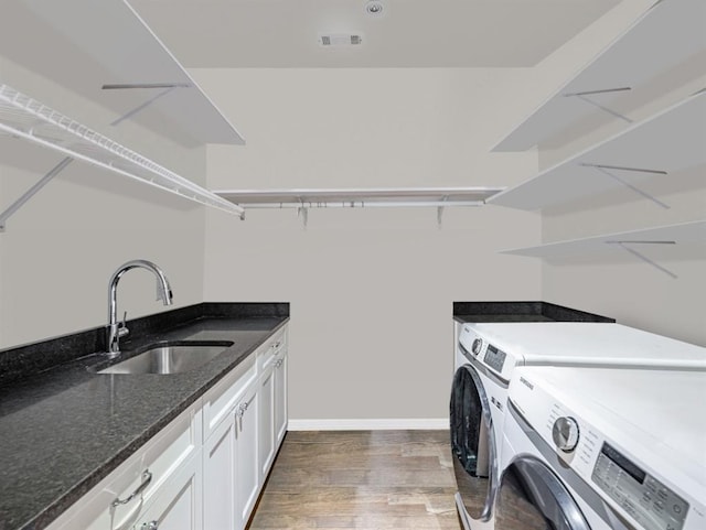 laundry area featuring washing machine and clothes dryer, cabinet space, visible vents, dark wood-type flooring, and a sink