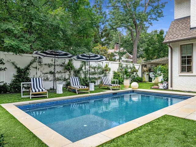 view of swimming pool with a fenced in pool, a fenced backyard, and a lawn