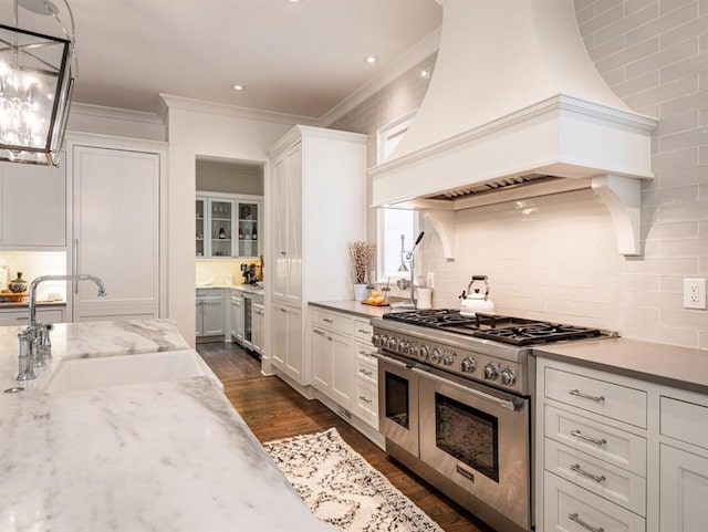 kitchen with pendant lighting, custom exhaust hood, white cabinets, and double oven range