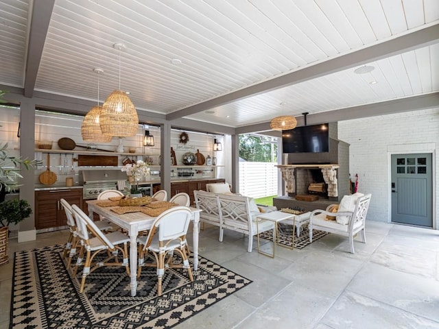 dining area with a fireplace with raised hearth, brick wall, and beam ceiling