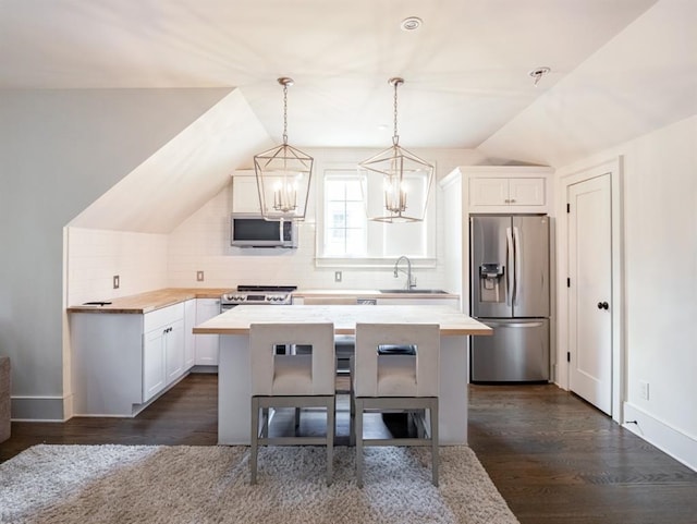 kitchen with stainless steel appliances, a sink, a kitchen island, white cabinets, and light countertops