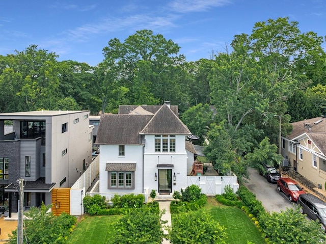 view of front facade featuring stucco siding, a shingled roof, fence, and a front yard