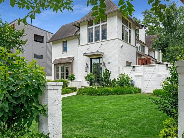 back of property with brick siding, a lawn, and a gate