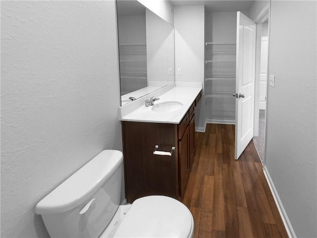 bathroom featuring baseboards, vanity, toilet, and wood finished floors