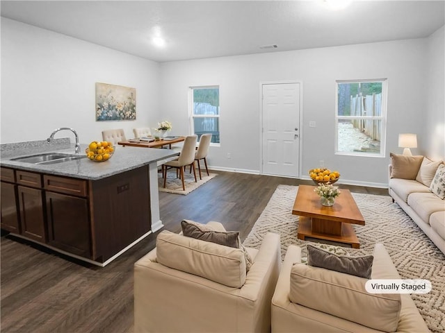 living room with a healthy amount of sunlight, dark wood finished floors, visible vents, and baseboards