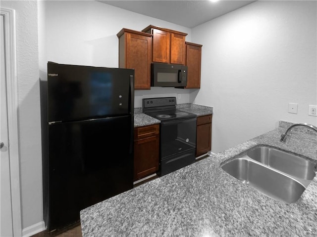 kitchen with brown cabinets, a sink, and black appliances