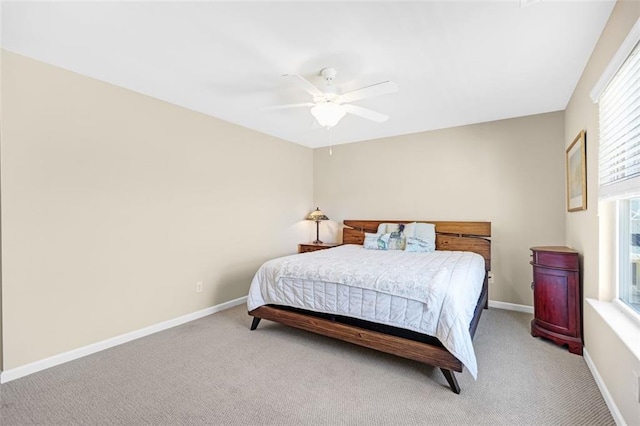 bedroom featuring a ceiling fan, baseboards, light wood-style flooring, and a tray ceiling