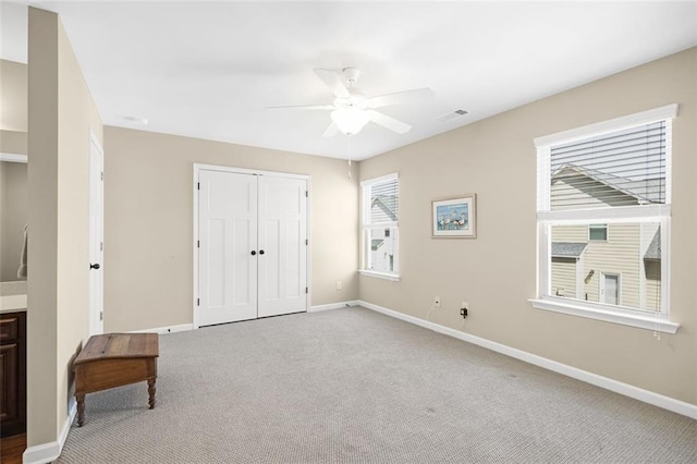 bedroom featuring baseboards, multiple windows, ceiling fan, and light colored carpet