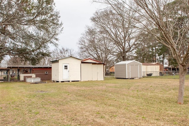 view of yard featuring a storage shed, fence, and an outbuilding