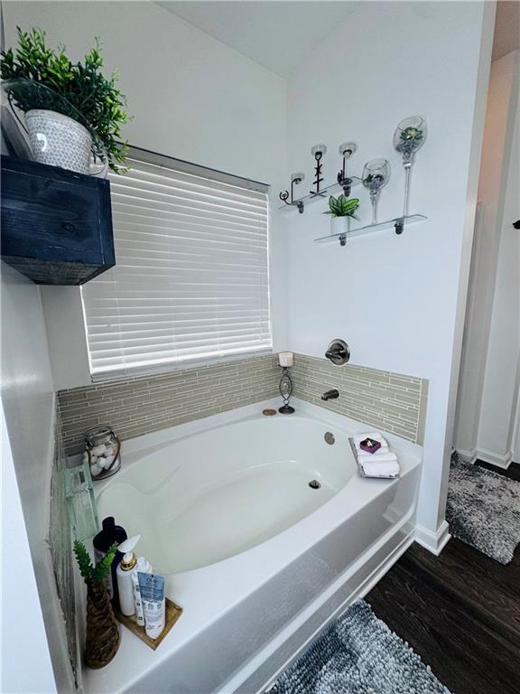 bathroom with a washtub and hardwood / wood-style flooring