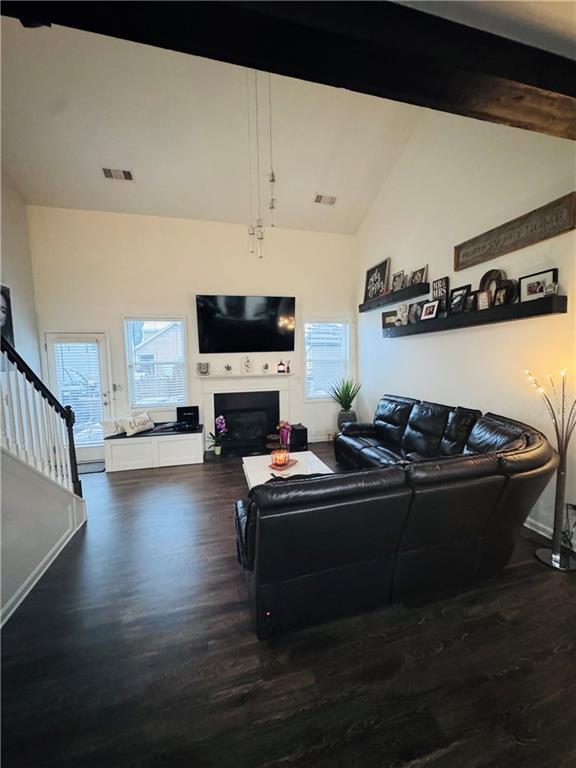 living room with wood-type flooring and vaulted ceiling with beams