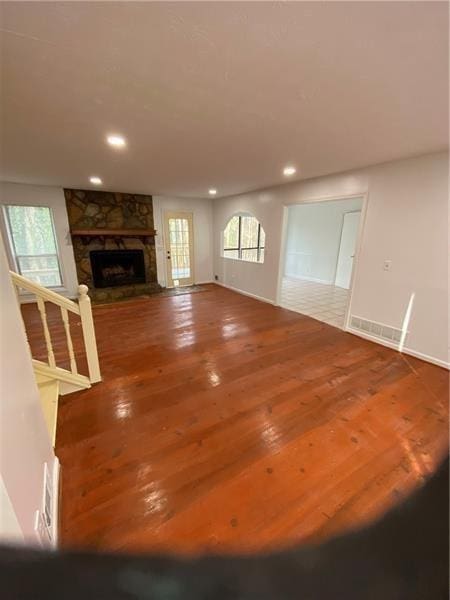 unfurnished living room featuring a stone fireplace, wood-type flooring, and recessed lighting