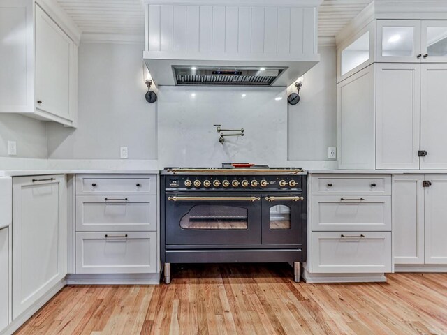 kitchen featuring white cabinetry, crown molding, island range hood, high end range, and light wood-type flooring