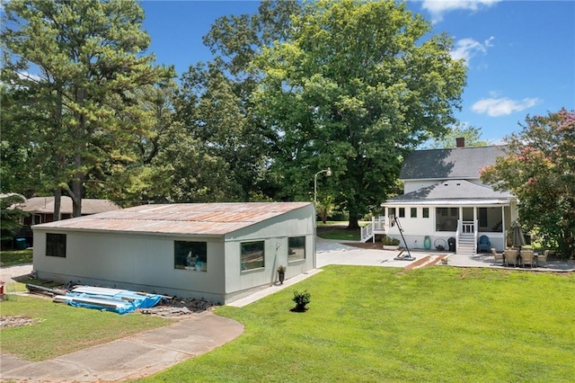 rear view of house with a lawn, a patio area, and a sunroom