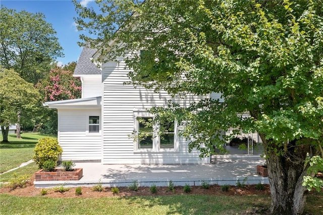 view of side of property with a patio area and a lawn