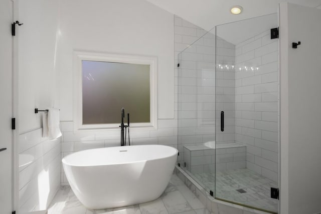 907 Edgewood Ave NE, Atlanta, GA 30307 - bathroom featuring marble look tile flooring, a soaking tub, a shower stall, and tile walls