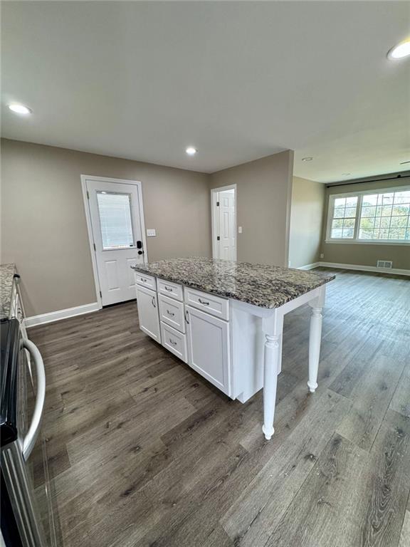 kitchen with white cabinets, dark wood-type flooring, and a kitchen island