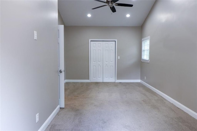 unfurnished bedroom with a closet, light colored carpet, and ceiling fan