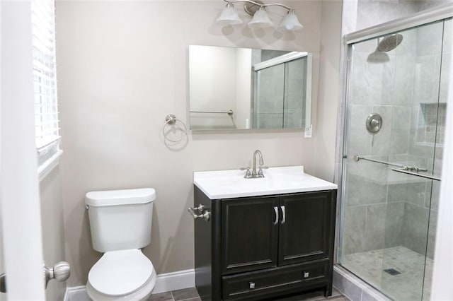 bathroom featuring tile patterned floors, vanity, toilet, and a shower with shower door