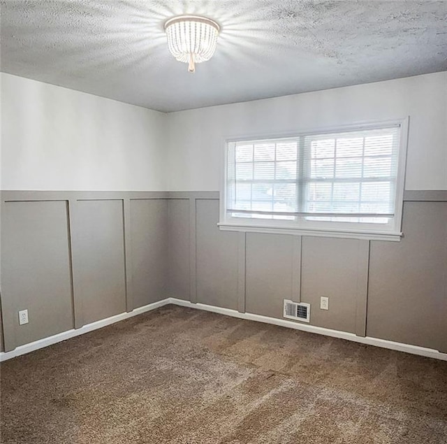 spare room with a textured ceiling and dark carpet